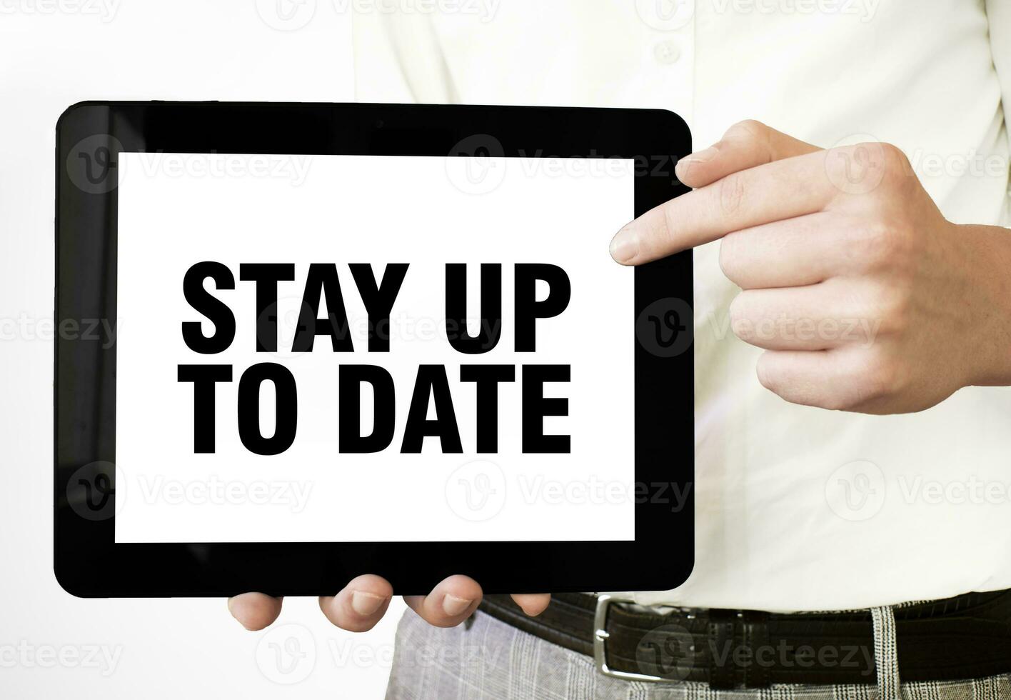 Text STAY UP TO DATE on tablet display in businessman hands on the white background. Business concept photo