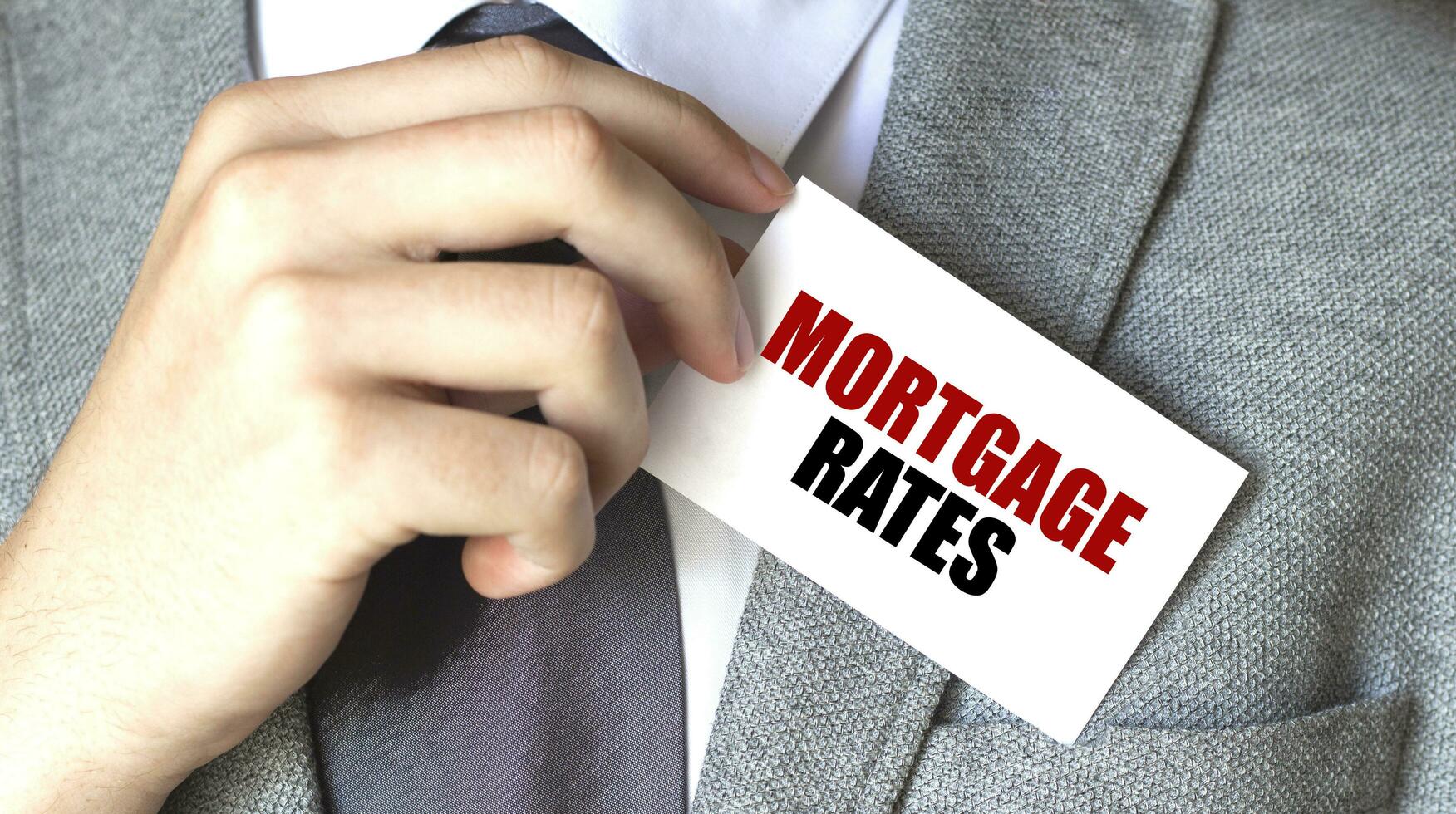 Businessman putting a card with text MORTGAGE RATES in the pocket photo