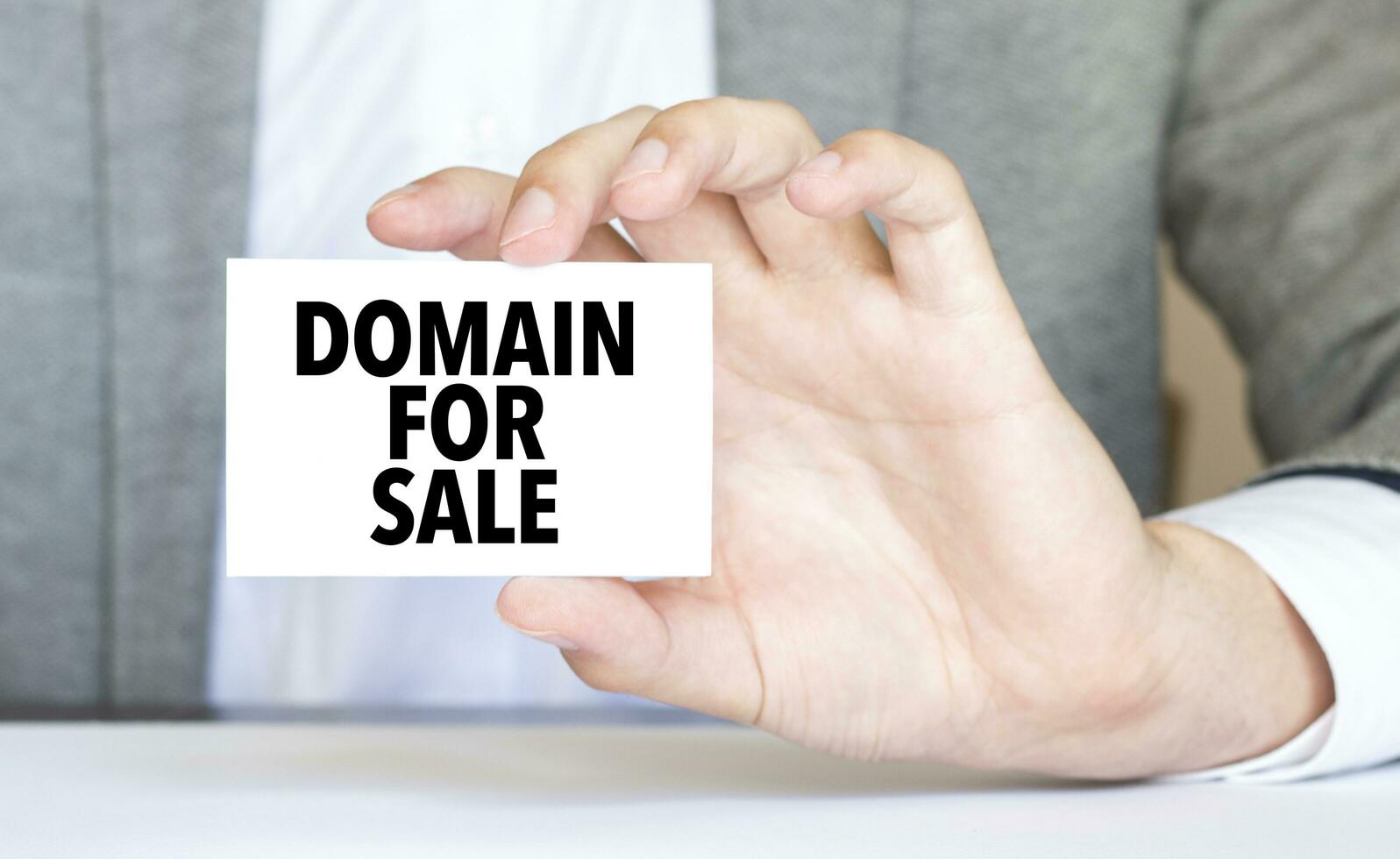 Businessman holding a card with text DOMAIN FOR SALE photo