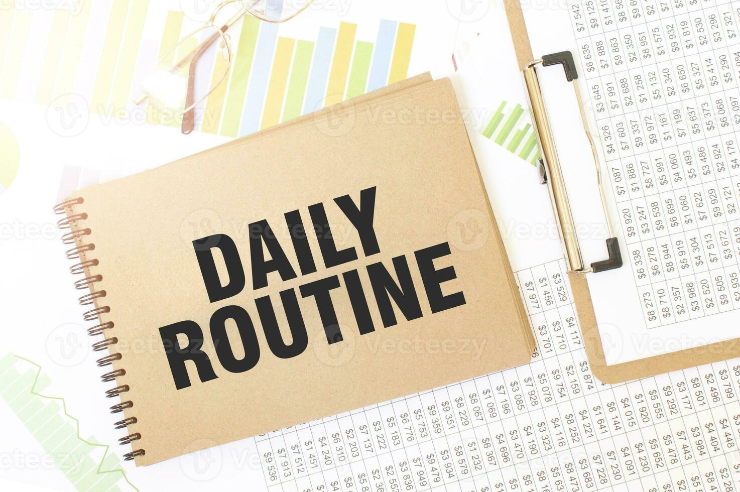 Business up graph on a sheet of craft colour Notepad with DAILY ROUTINE sign. Notepad on desk with financial documentation photo