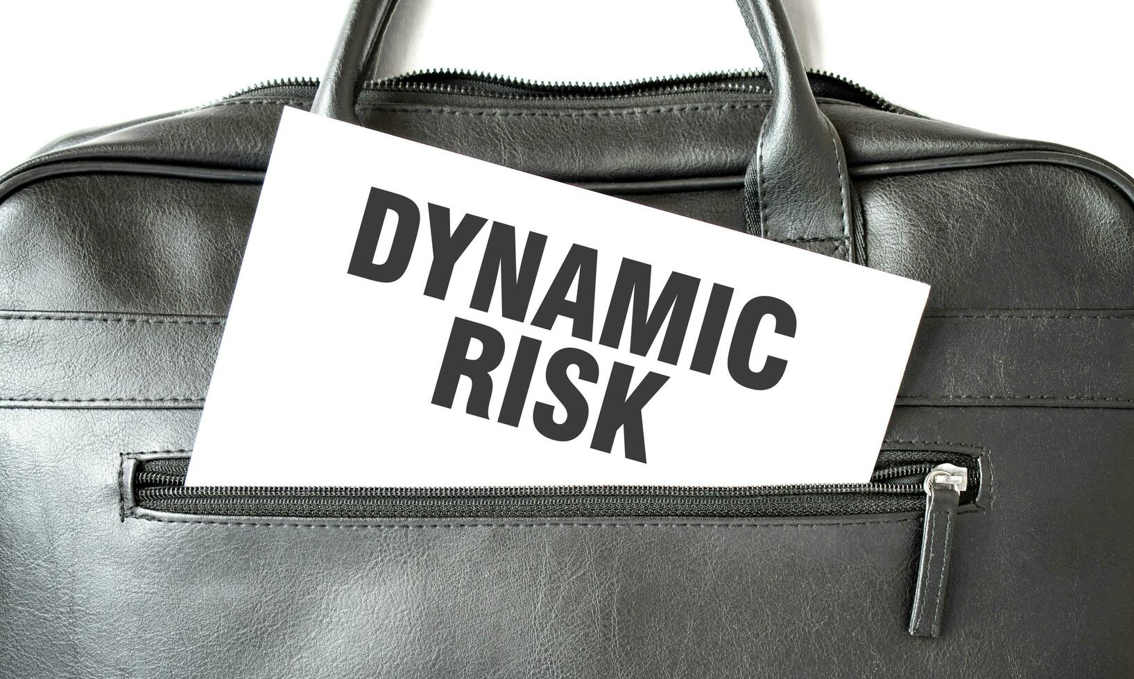 Text DYNAMIC RISK writing on white paper sheet in the black business bag. Business concept photo