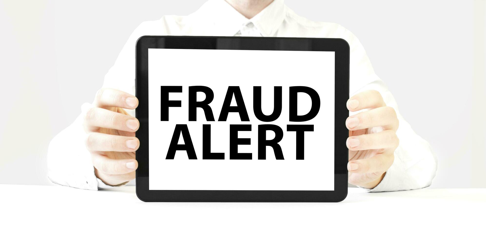 Text fraud alert on tablet display in businessman hands on the white background. Business concept photo