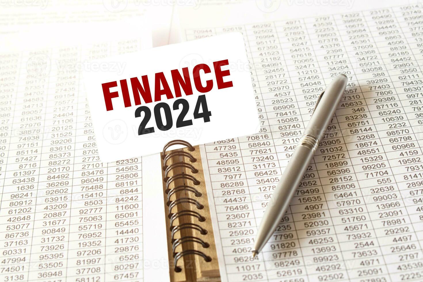 Text FINANCE 2024 on paper card, pen, financial documentation on table photo