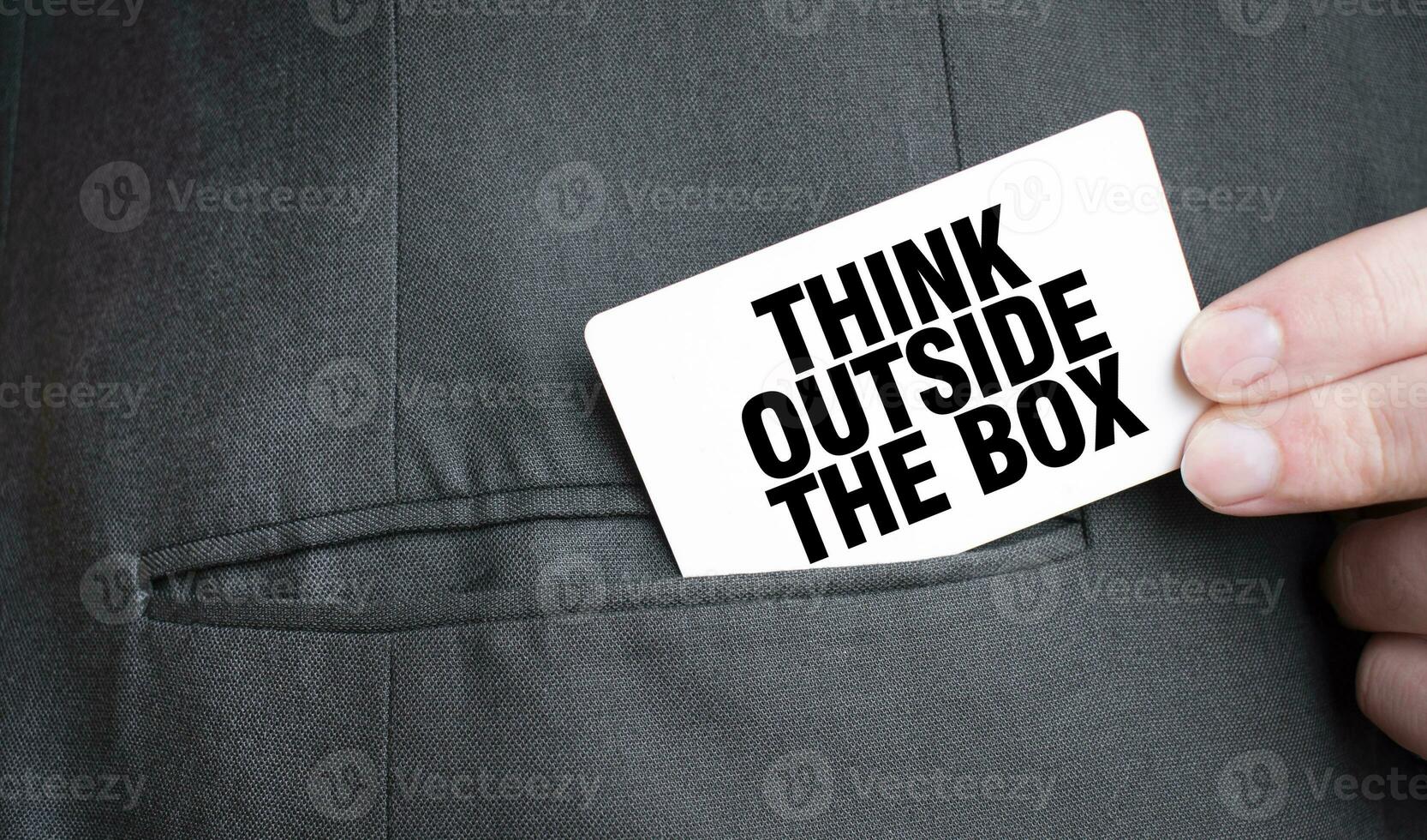 Card with THINK OUTSIDE THE BOX text in pocket of businessman suit. Investment and decisions business concept. photo