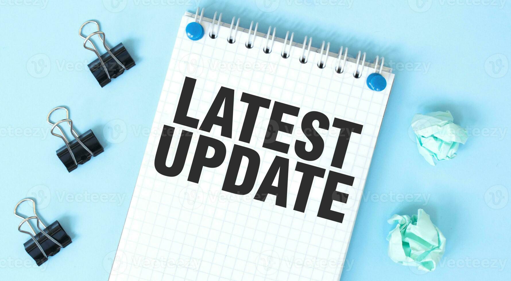 White notepad with text LATEST UPDATE and office tools on the blue background photo