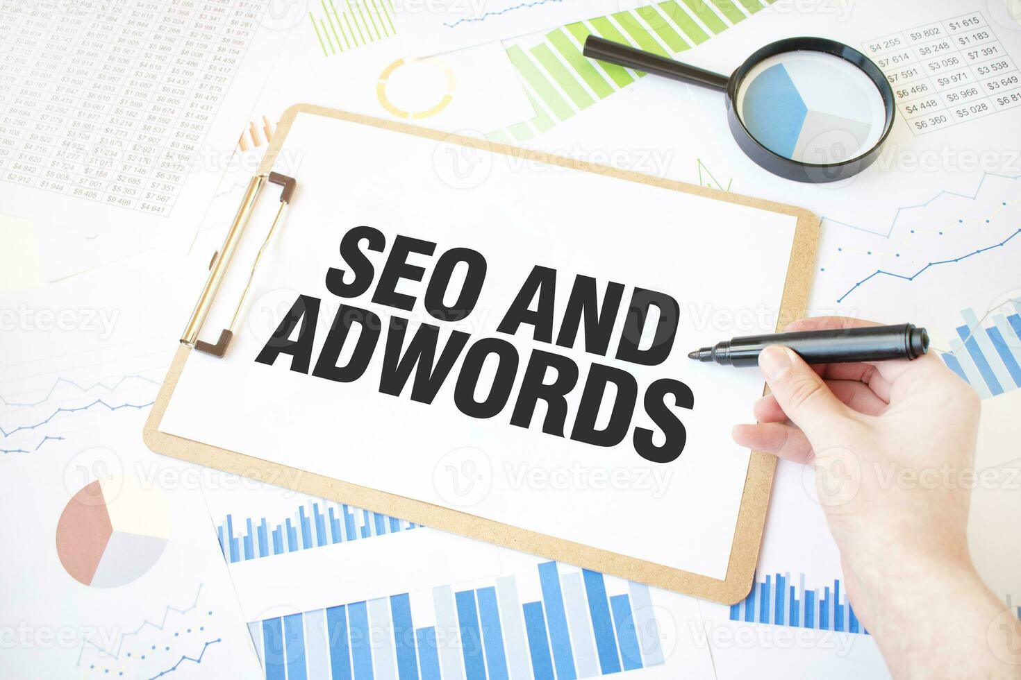 Text SEO AND ADWORDS on white paper sheet and marker on businessman hand on the diagram. Business concept photo