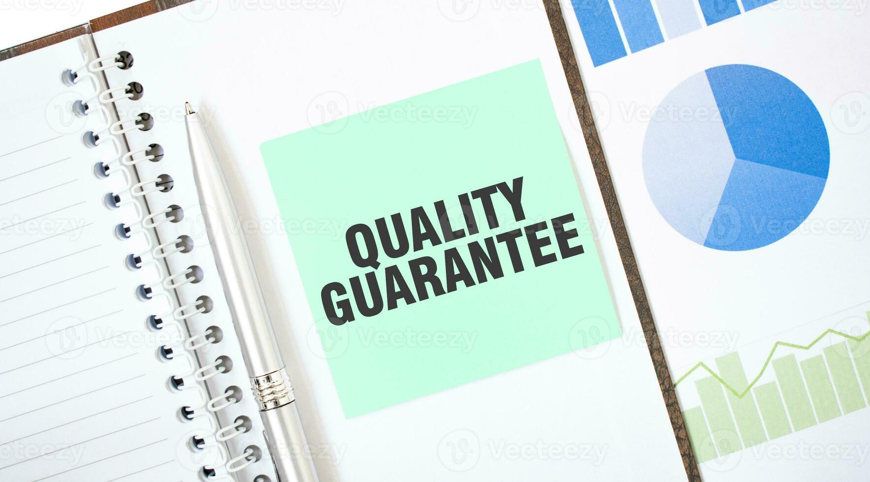 Green card on the white notepad. Text QUALITY GUARANTEE. Business concept photo