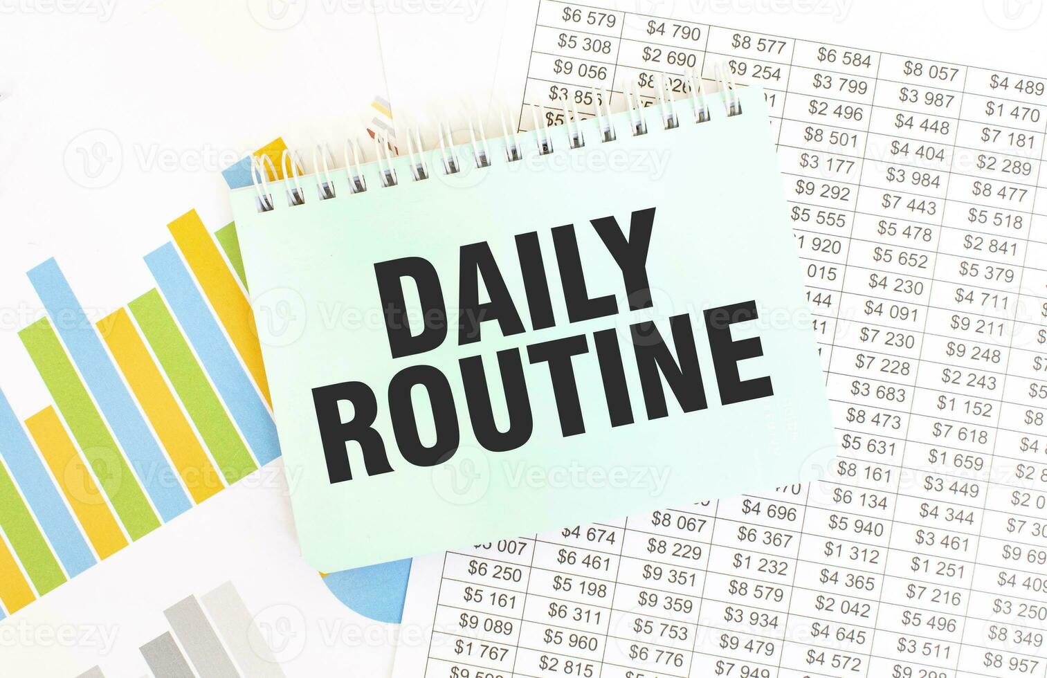 Green notepad on financial documentation. Text DAILY ROUTINe. Business concept photo