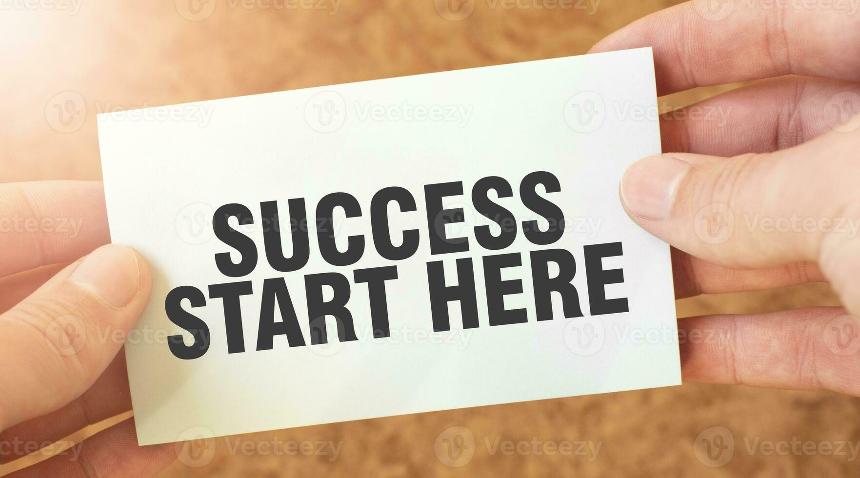SUCCESS START HERE word inscription on white card paper sheet in hands of a businessman. photo