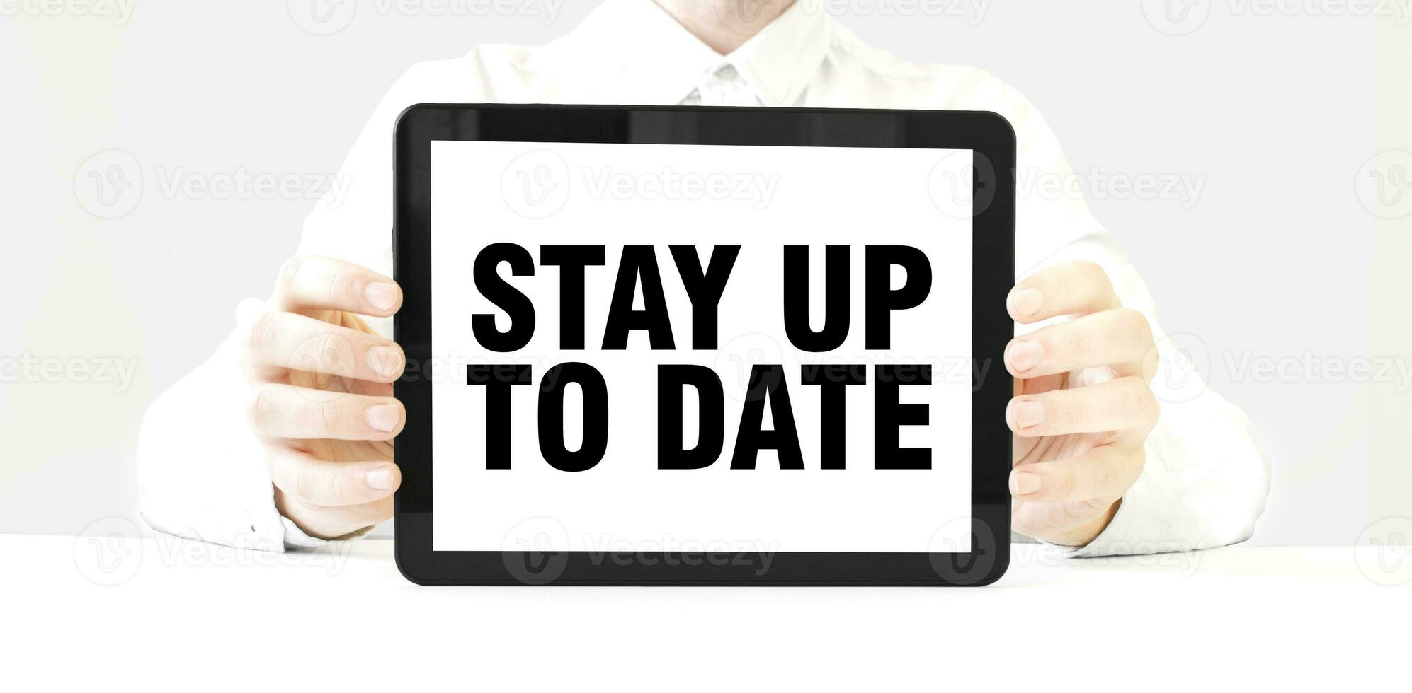 Text STAY UP TO DATE on tablet display in businessman hands on the white background. Business concept photo