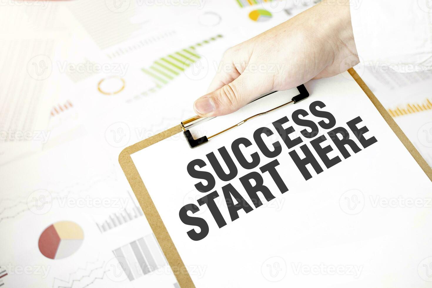 Text SUCCESS START HERE on white paper plate in businessman hands with financial diagram. Business concept photo