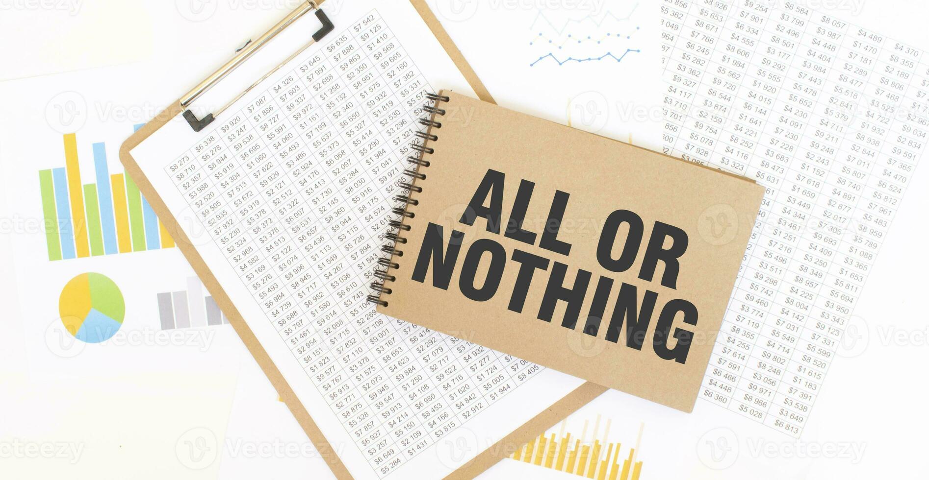 Text ALL OR NOTHING on brown paper notepad on the table with diagram. Business concept photo