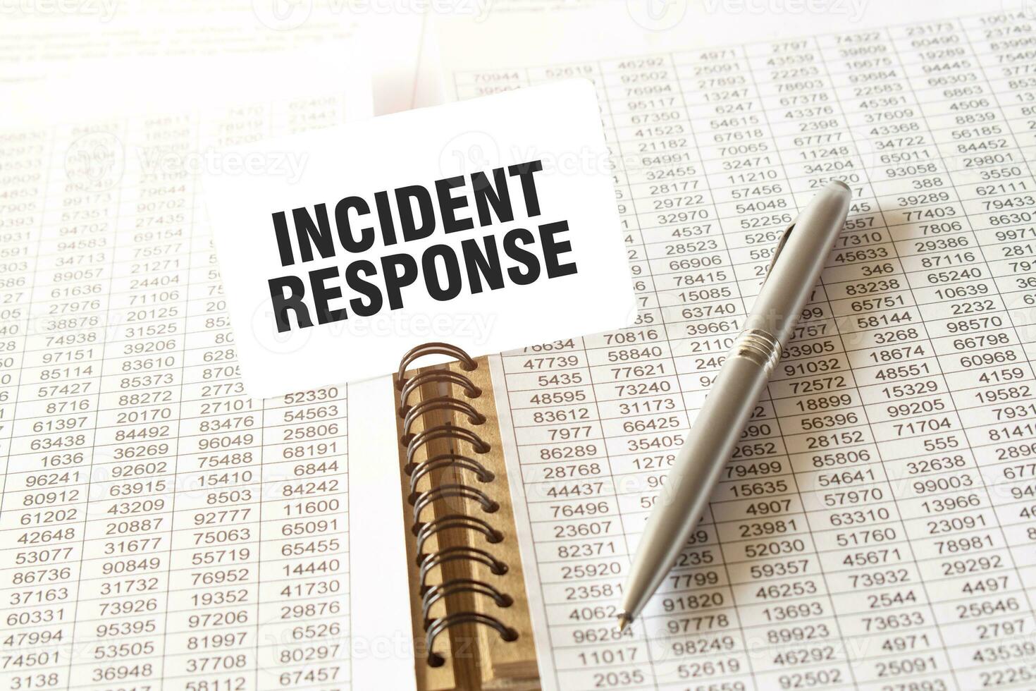 Text INCIDENT RESPONSE on paper card, pen, financial documentation on table photo