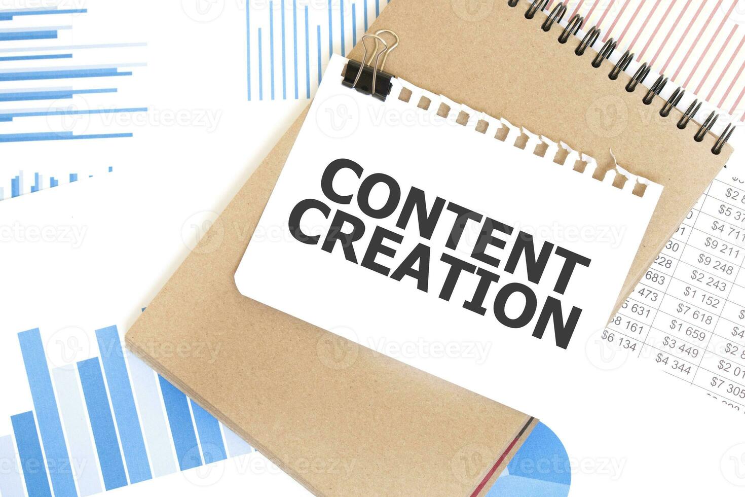 Text CONTENT CREATION on white paper sheet and brown paper notepad on the table with diagram. Business concept photo