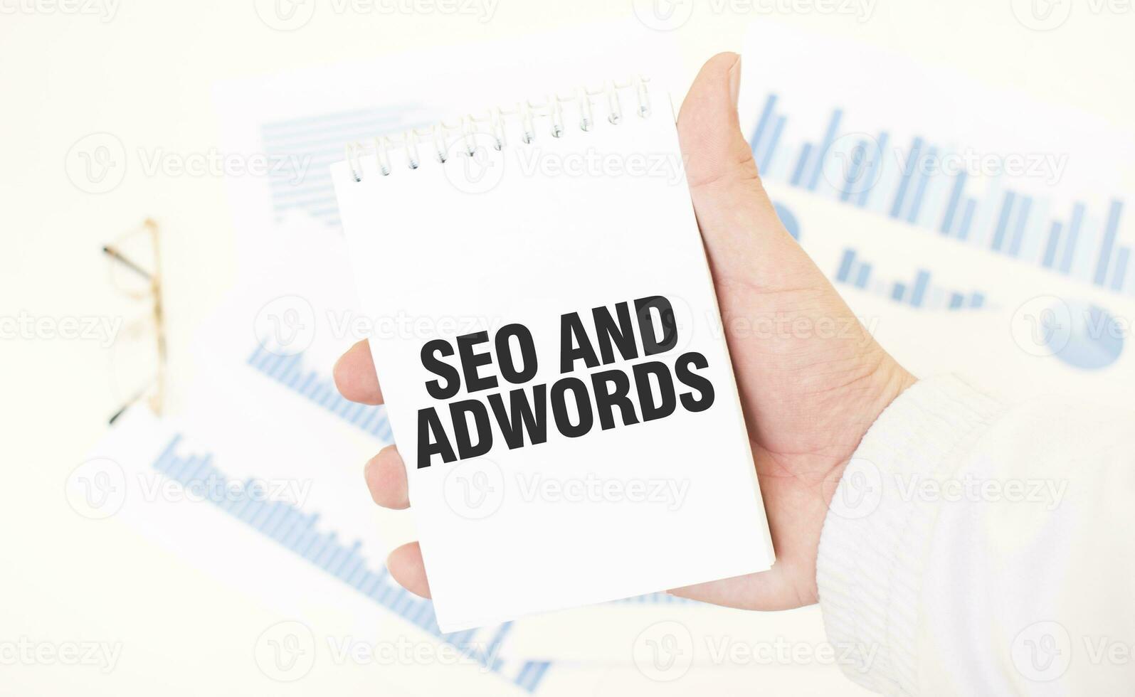 Businessman holding a white notepad with text SEO AND ADWORDS, business concept photo