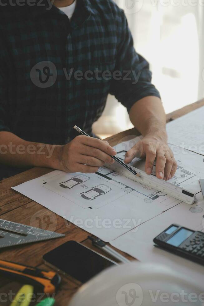 Close up of civil male engineer asian working on blueprint architectural project at construction site at desk in office. photo