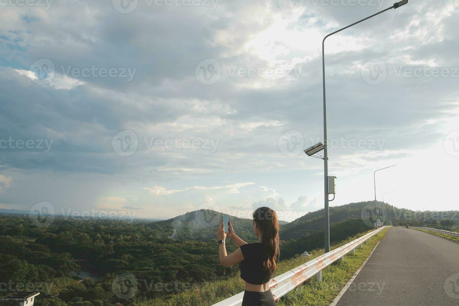 Young woman traveler in casual clothes with backpack from back on background of beautiful view on mountains photo