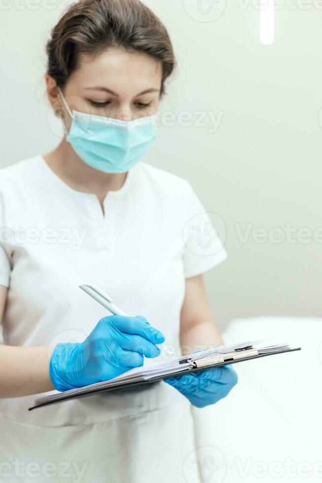 Cosmetologist consulting and making notes before face treatment photo