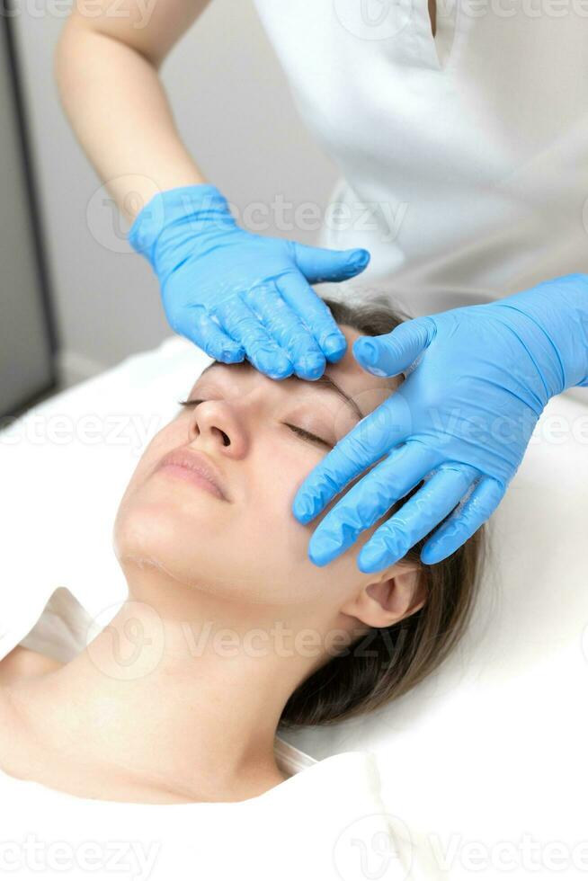 Woman receiving face treatment by cosmetologyst in beauty salon photo