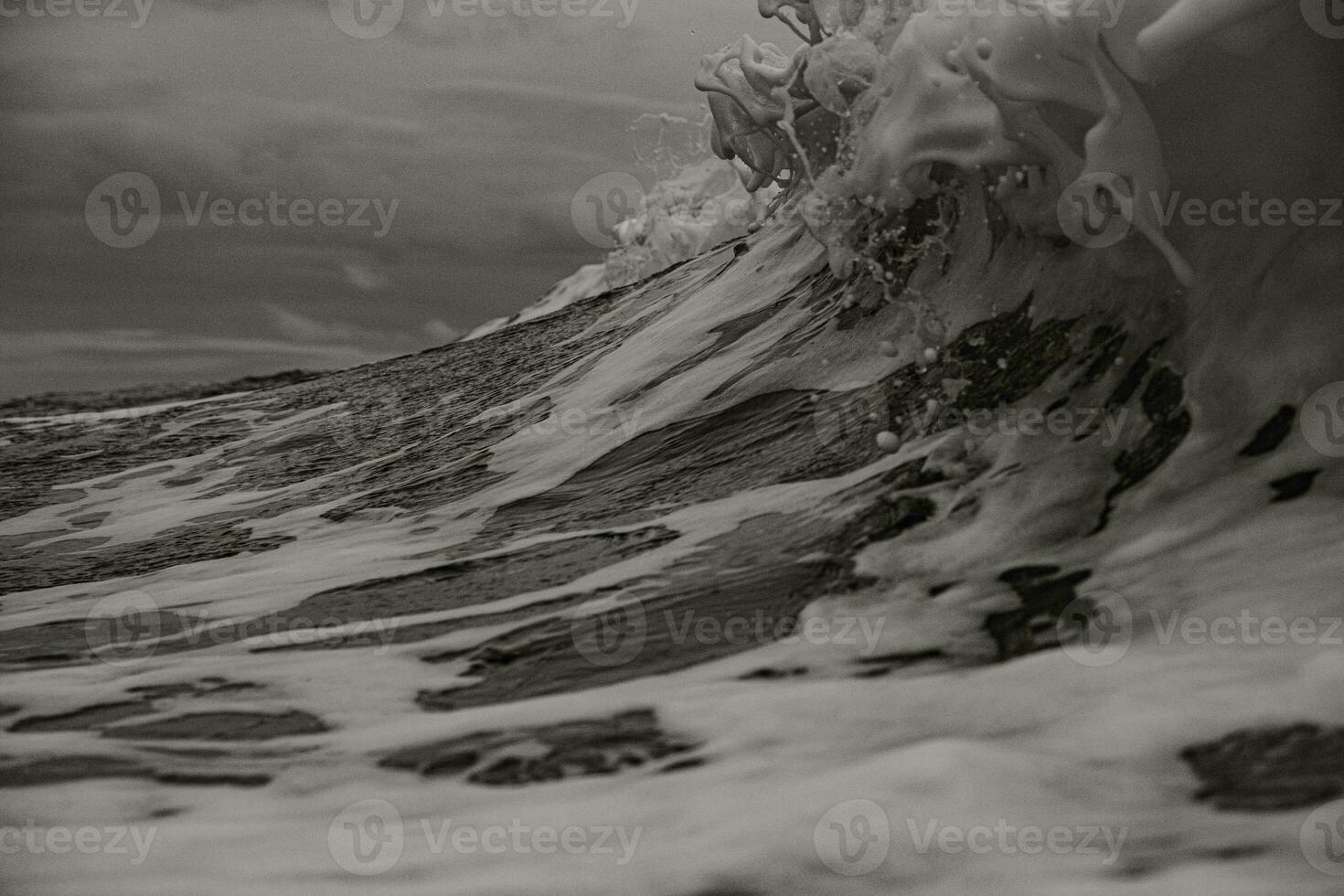 a black and white photo of a wave breaking