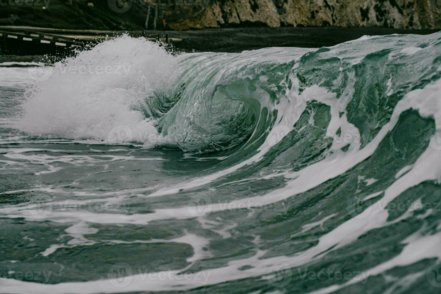 a wave breaking on the shore of an ocean photo