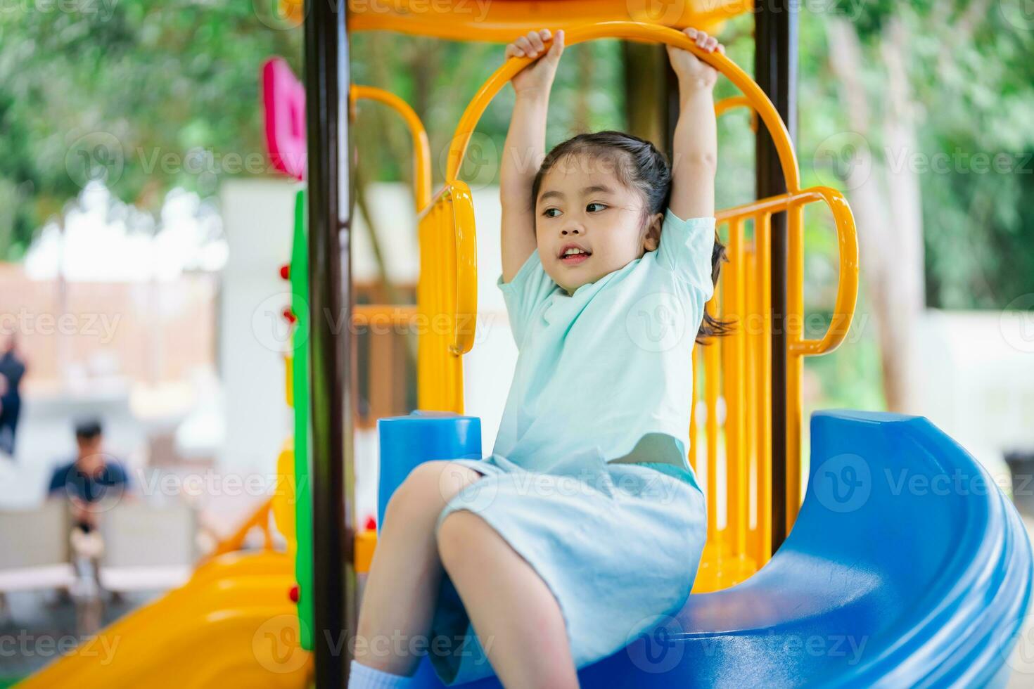 Cute asian girl smile play on school or kindergarten yard or playground. Healthy summer activity for children. Little asian girl climbing outdoors at playground. Child playing on outdoor playground. photo