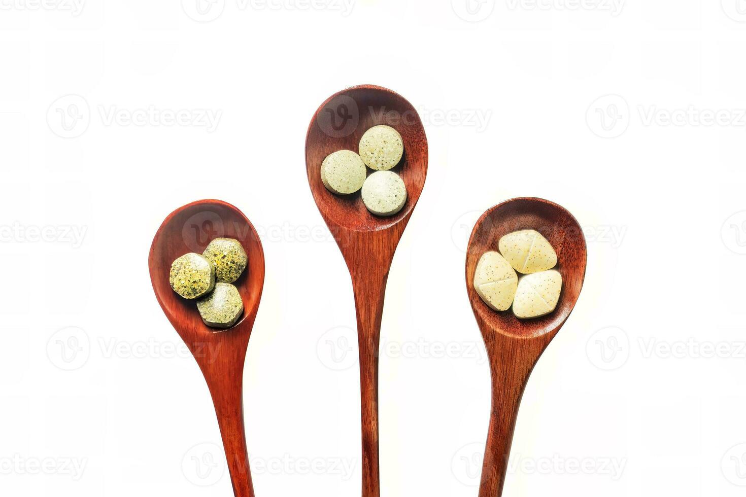 Multivitamins, multimineral, and phytonutrients are pressed tablets as nutritional supplements placed on a wooden spoon with isolated on white background. photo