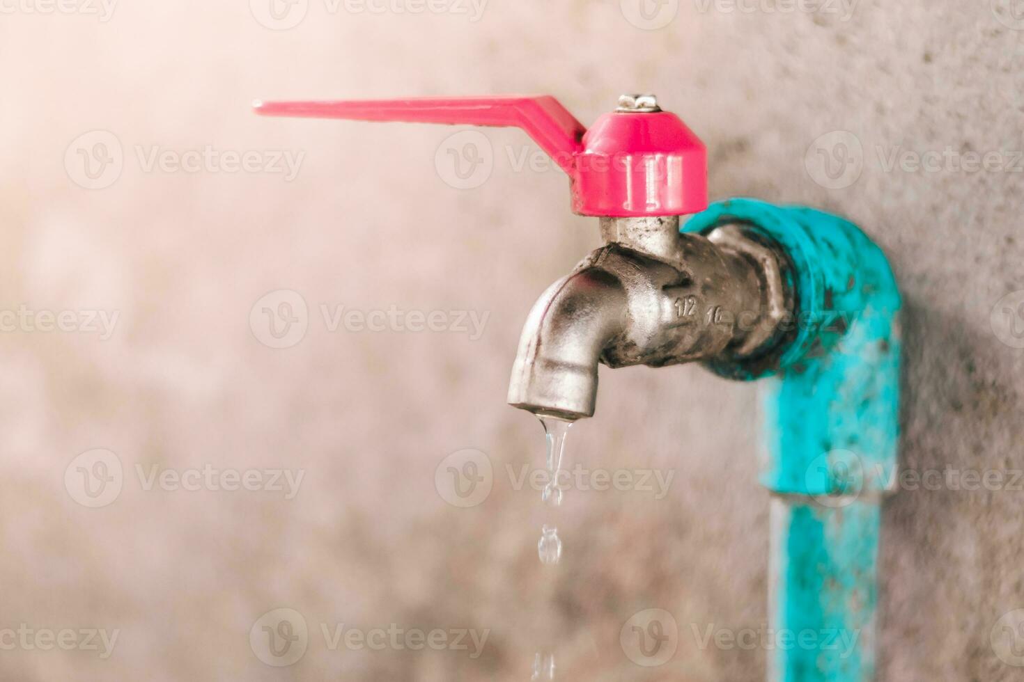 Shot of selective focus old faucet doesn't close properly and dripping water leaks out photo