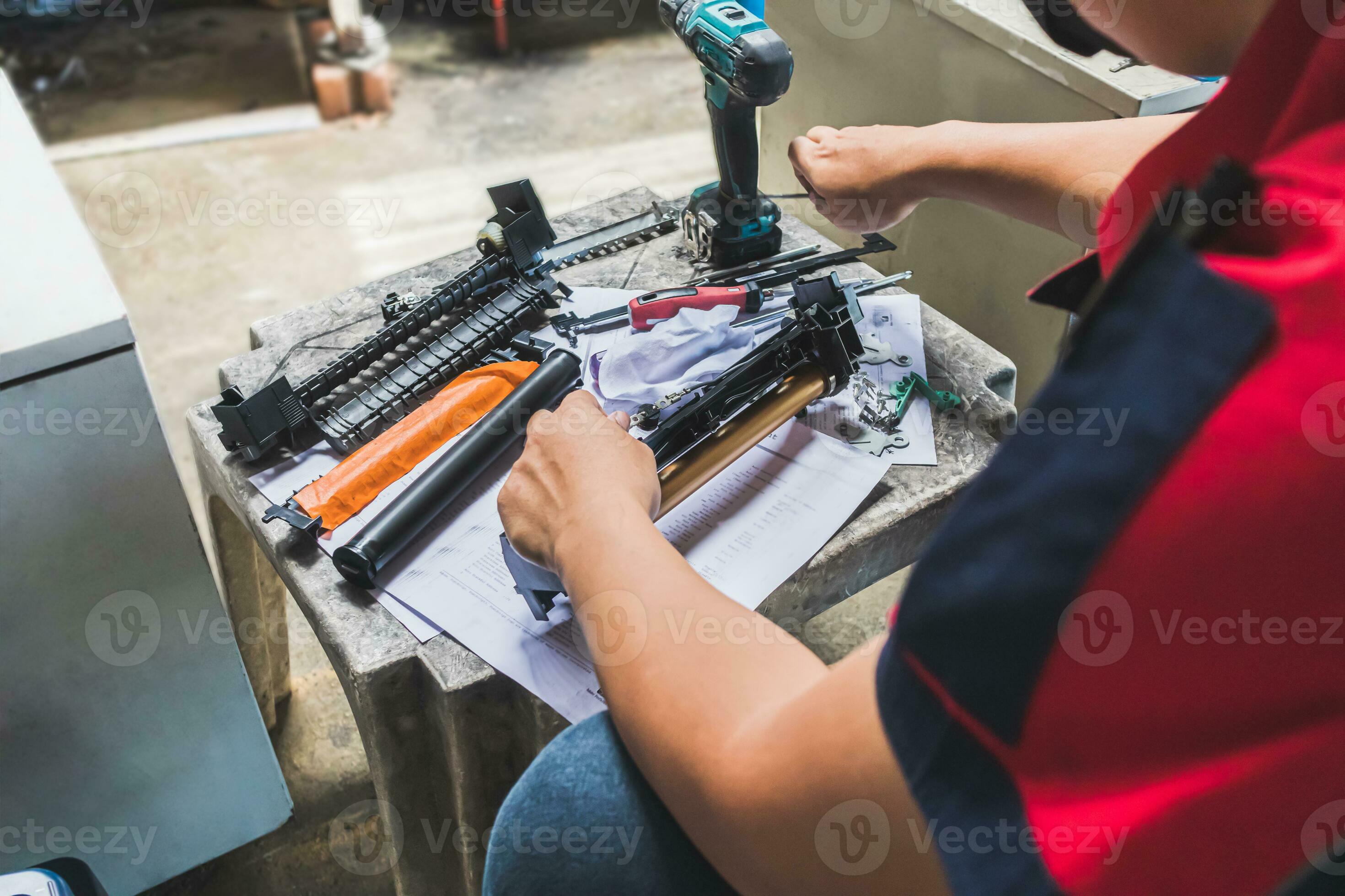 A technician man is repairing and cleaning drum of laser printer with