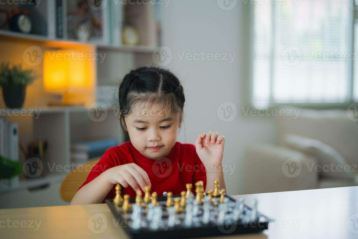 Education studying concept. Little cute asian baby girl children playing chess in the living room at home.Smart kid.fashion children. Little genius Child. Intelligent game.Chessboard. photo