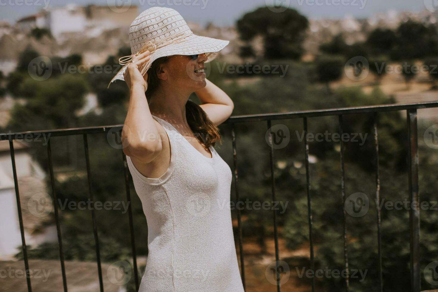 un joven mujer en un blanco vestir con blanco sombrero durante turista visitar en alberobello, Italia foto