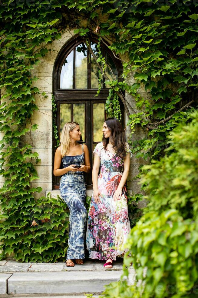 Pretty young women using mobile phone by the old house with ivy photo