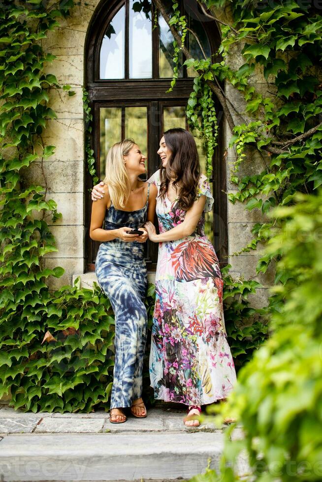 Pretty young women using mobile phone by the old house with ivy photo