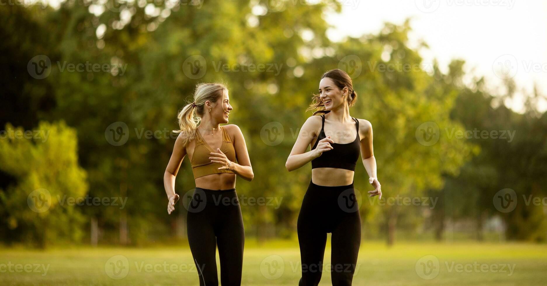 Two pretty young women running in the park photo