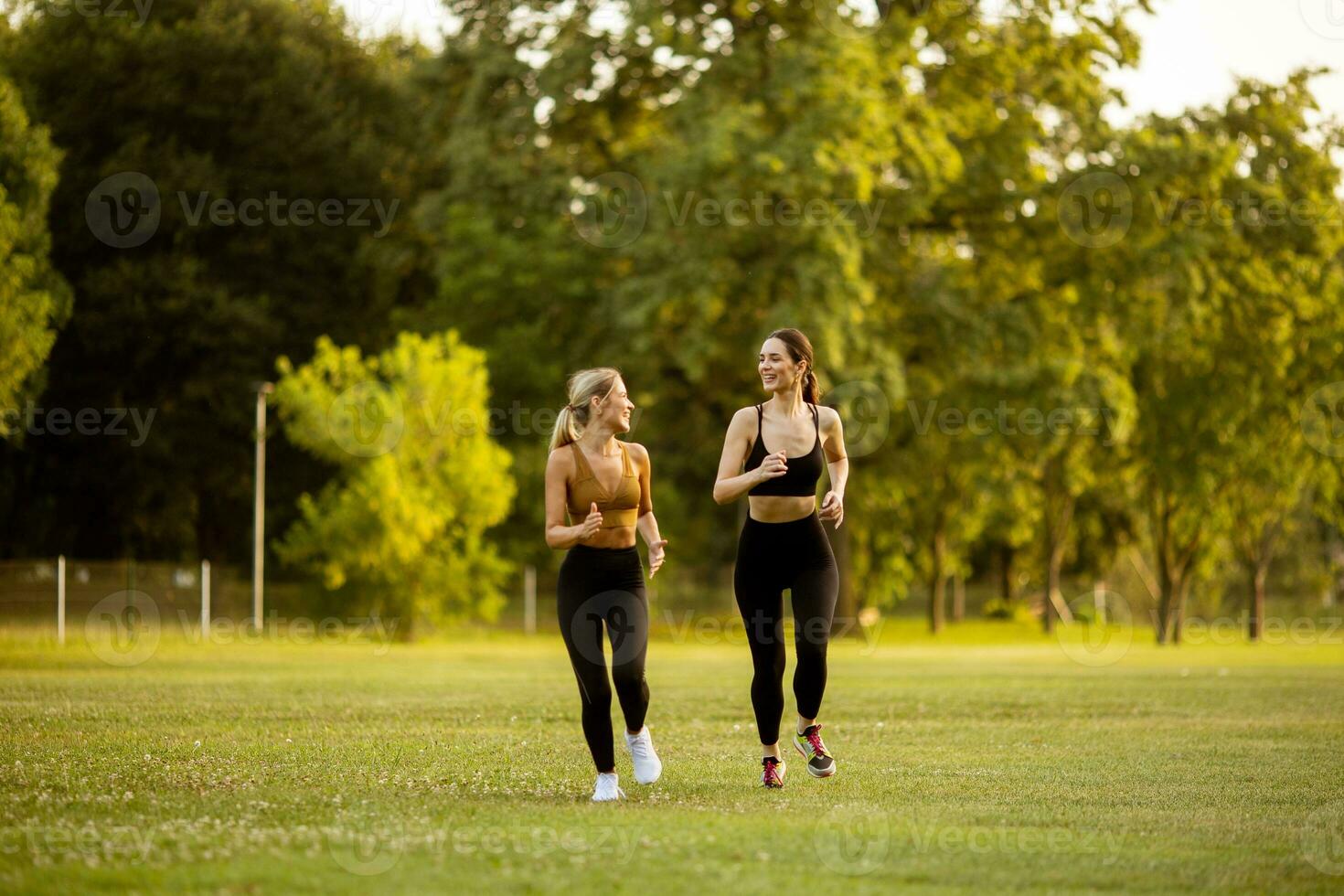 Two pretty young women running in the park photo