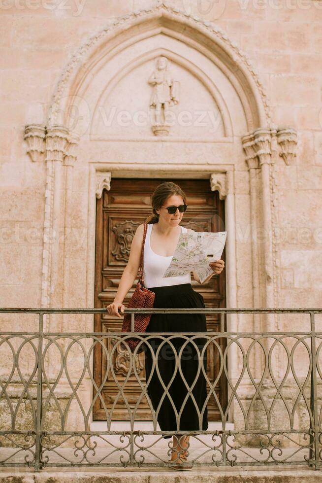 hembra turista con ciudad mapa por el Iglesia san francesco dassisi en ostuni, Italia foto