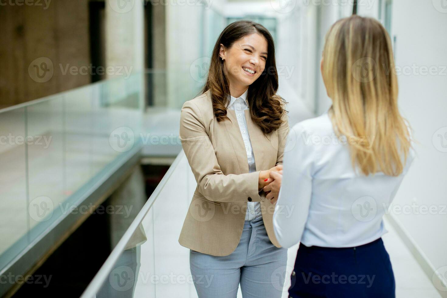 Two young business women handshaking  in the office hallway photo