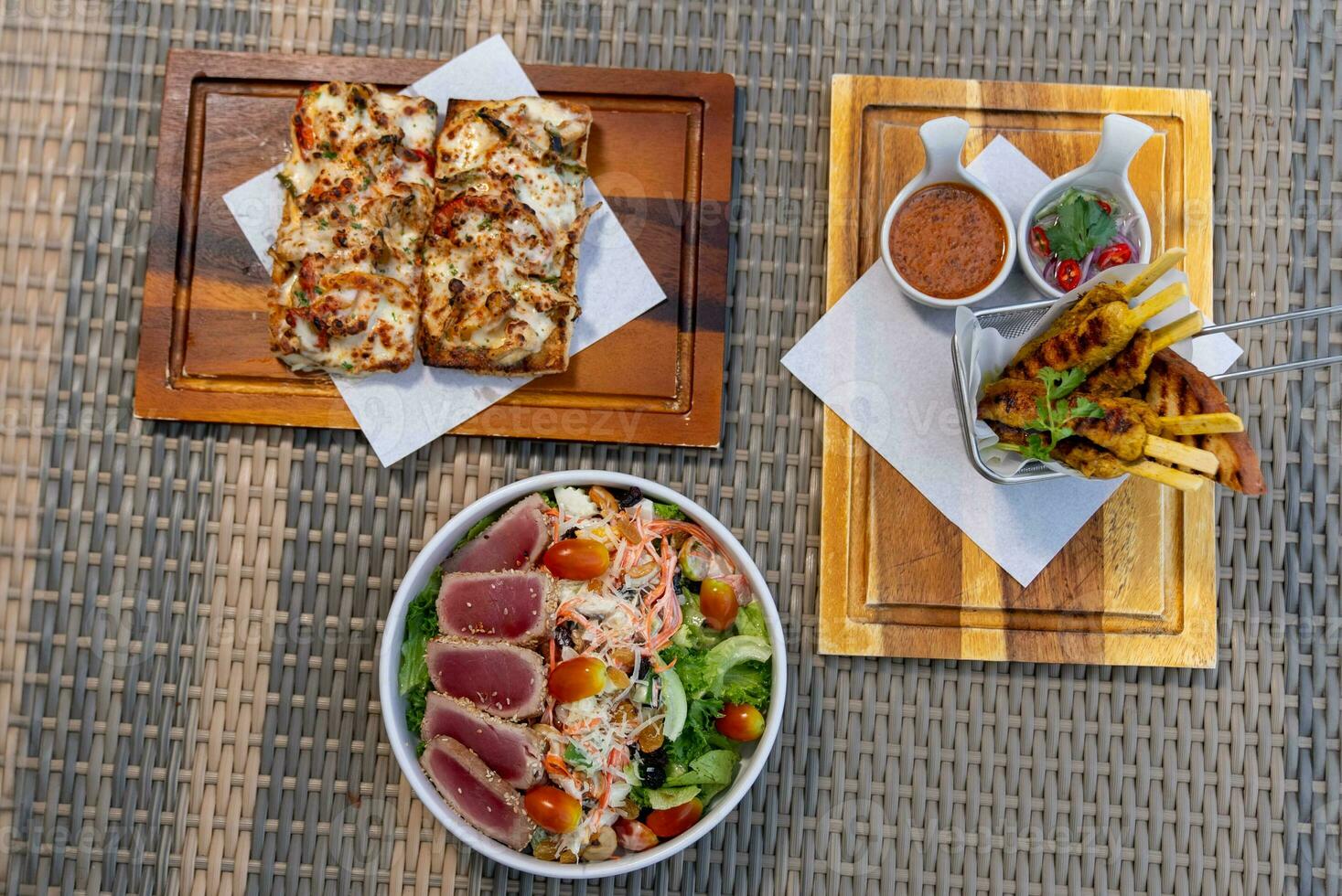 Spaghetti, pizza, french fries, beef steak on a wooden plate on the beach photo