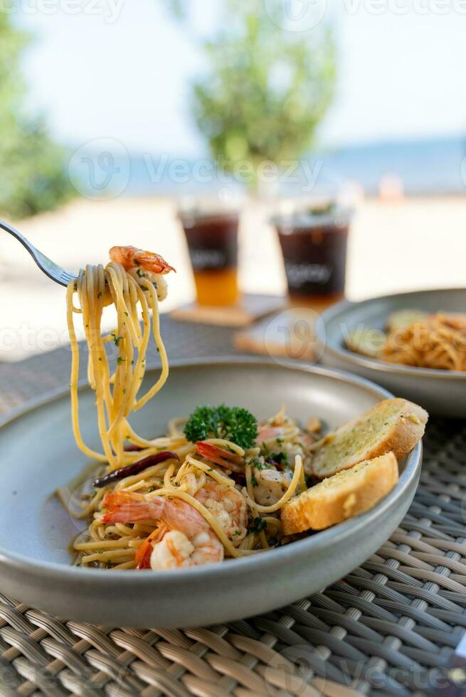 Spaghetti, pizza, french fries, beef steak on a wooden plate on the beach photo