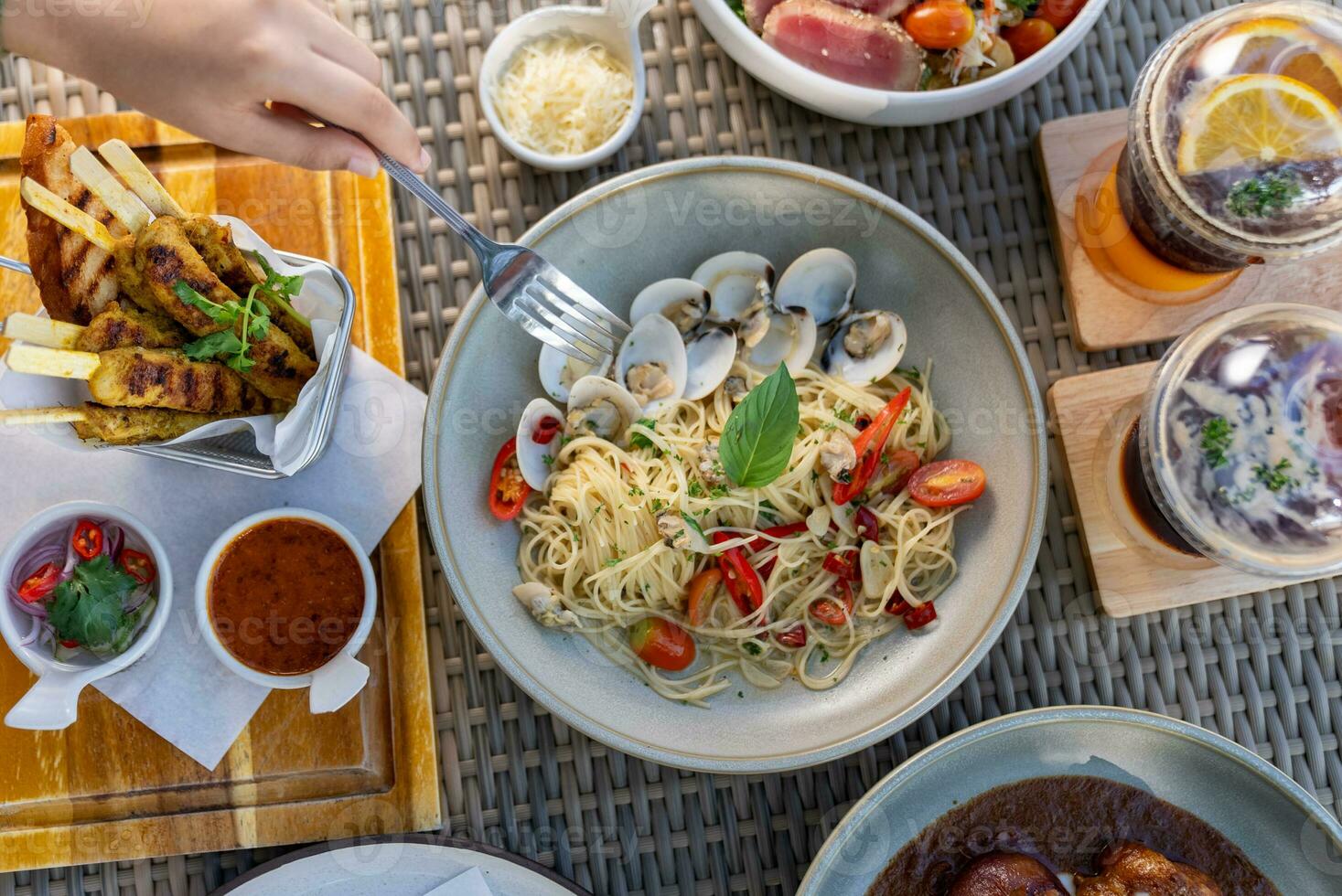 Spaghetti, pizza, french fries, beef steak on a wooden plate on the beach photo