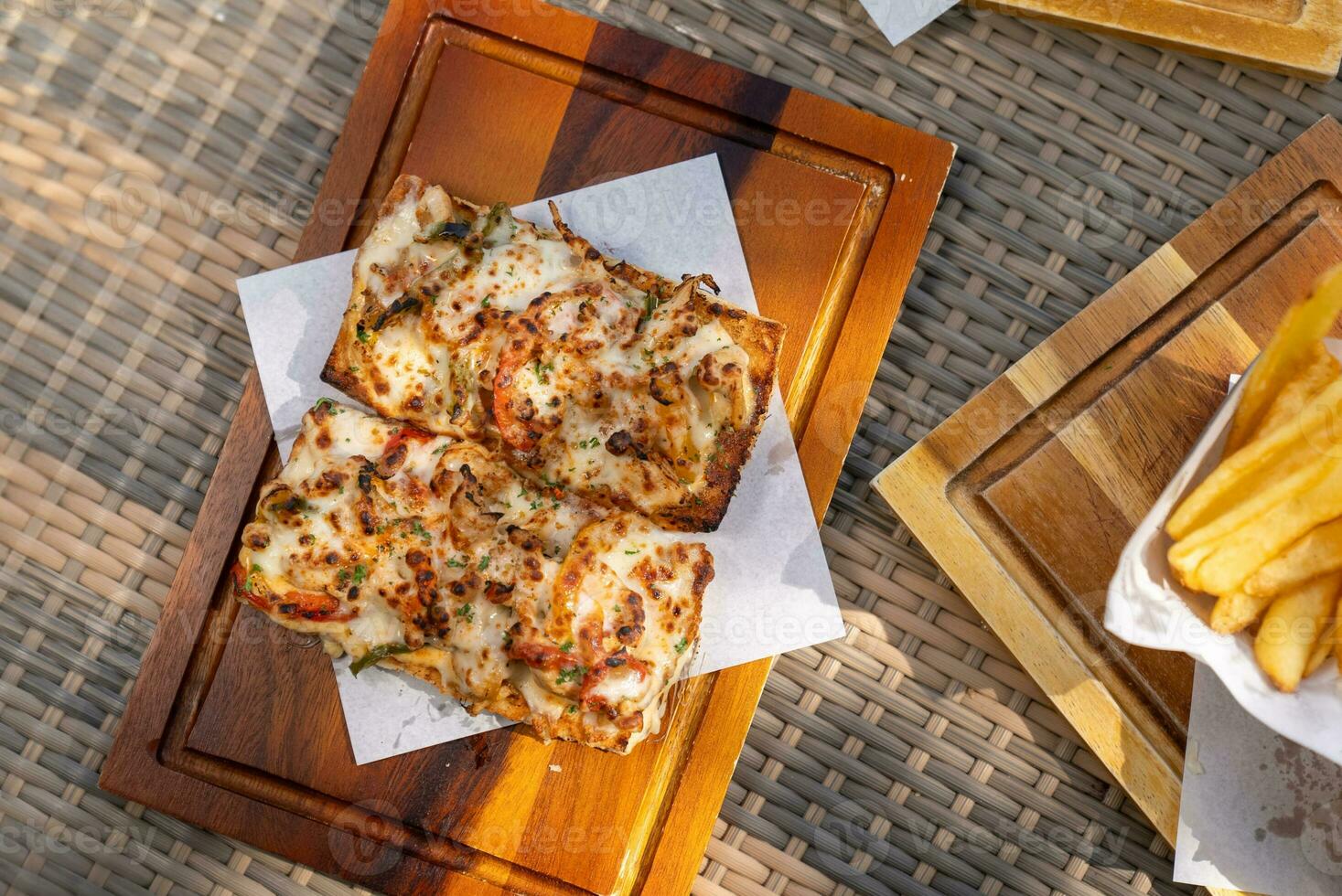 Spaghetti, pizza, french fries, beef steak on a wooden plate on the beach photo