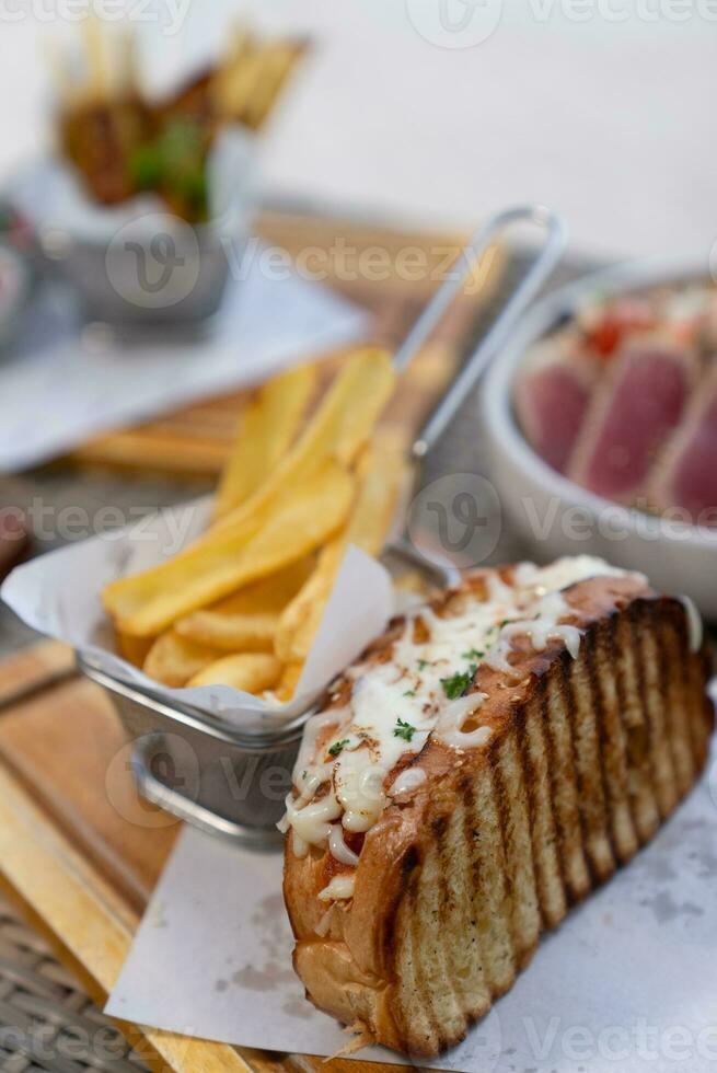 Spaghetti, pizza, french fries, beef steak on a wooden plate on the beach photo