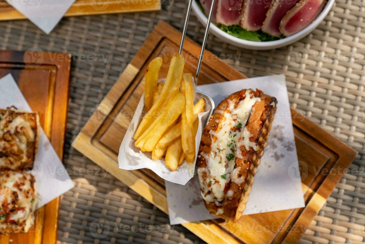 Spaghetti, pizza, french fries, beef steak on a wooden plate on the beach photo