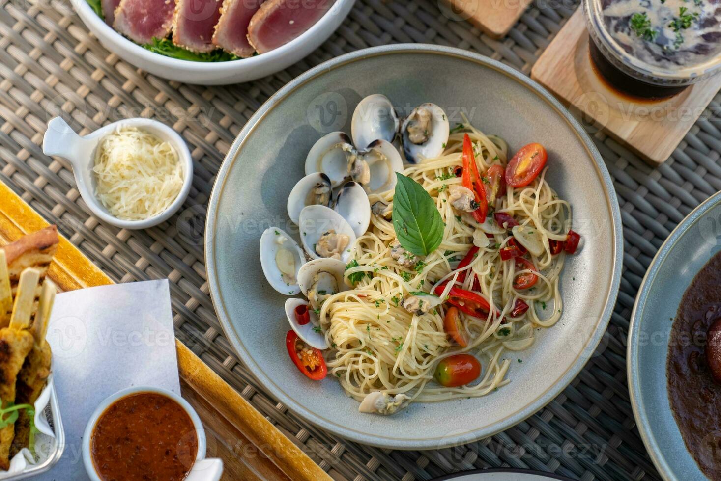 Spaghetti, pizza, french fries, beef steak on a wooden plate on the beach photo