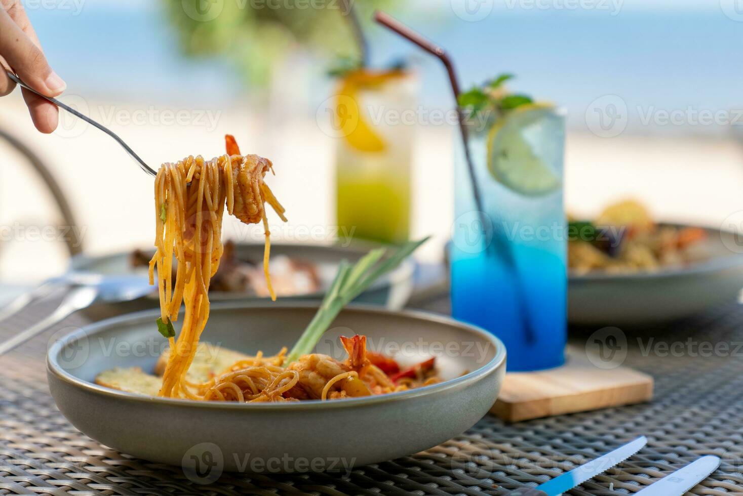 Spaghetti, pizza, french fries, beef steak on a wooden plate on the beach photo