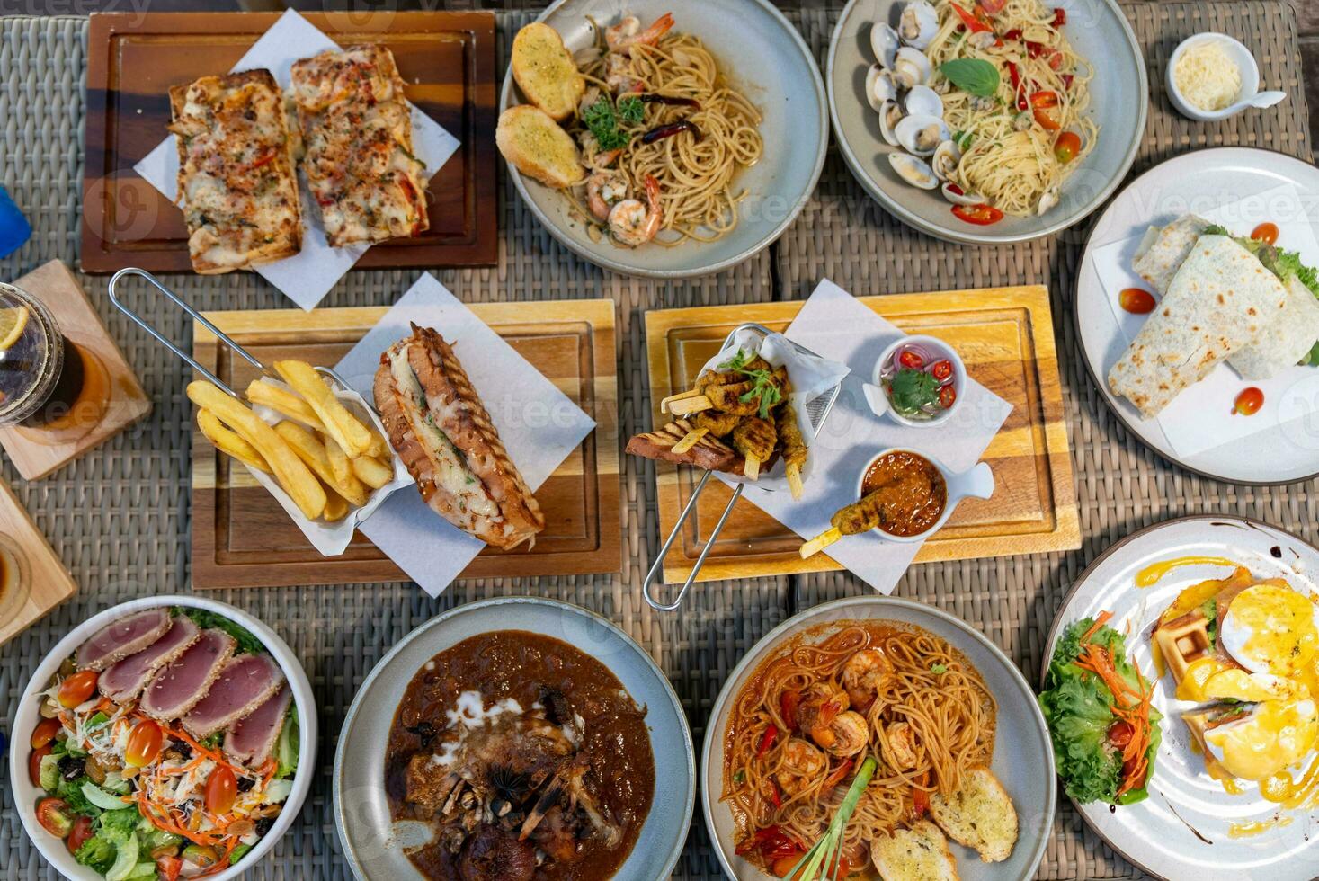 Spaghetti, pizza, french fries, beef steak on a wooden plate on the beach photo
