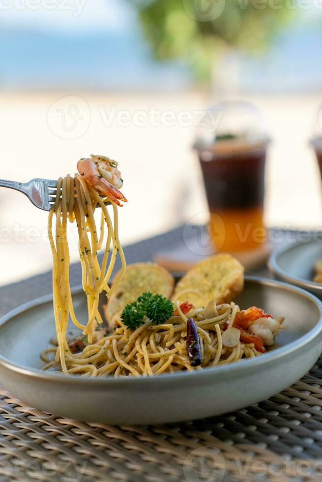 Spaghetti, pizza, french fries, beef steak on a wooden plate on the beach photo