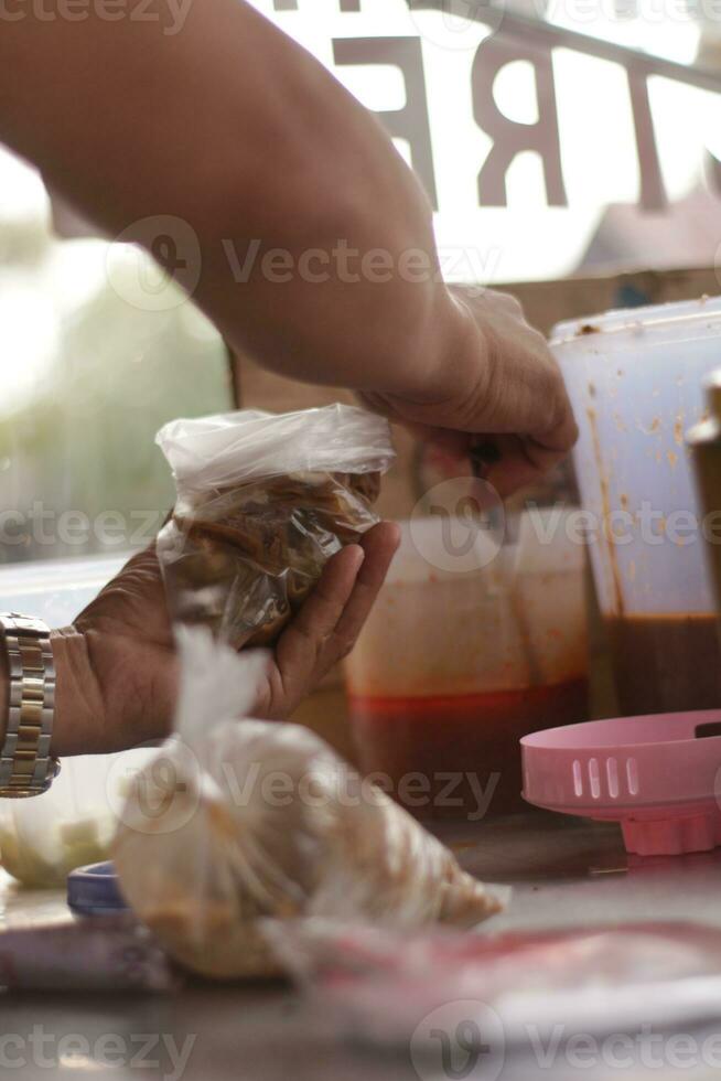 An Indonesian street food vendor preparing customer order photo