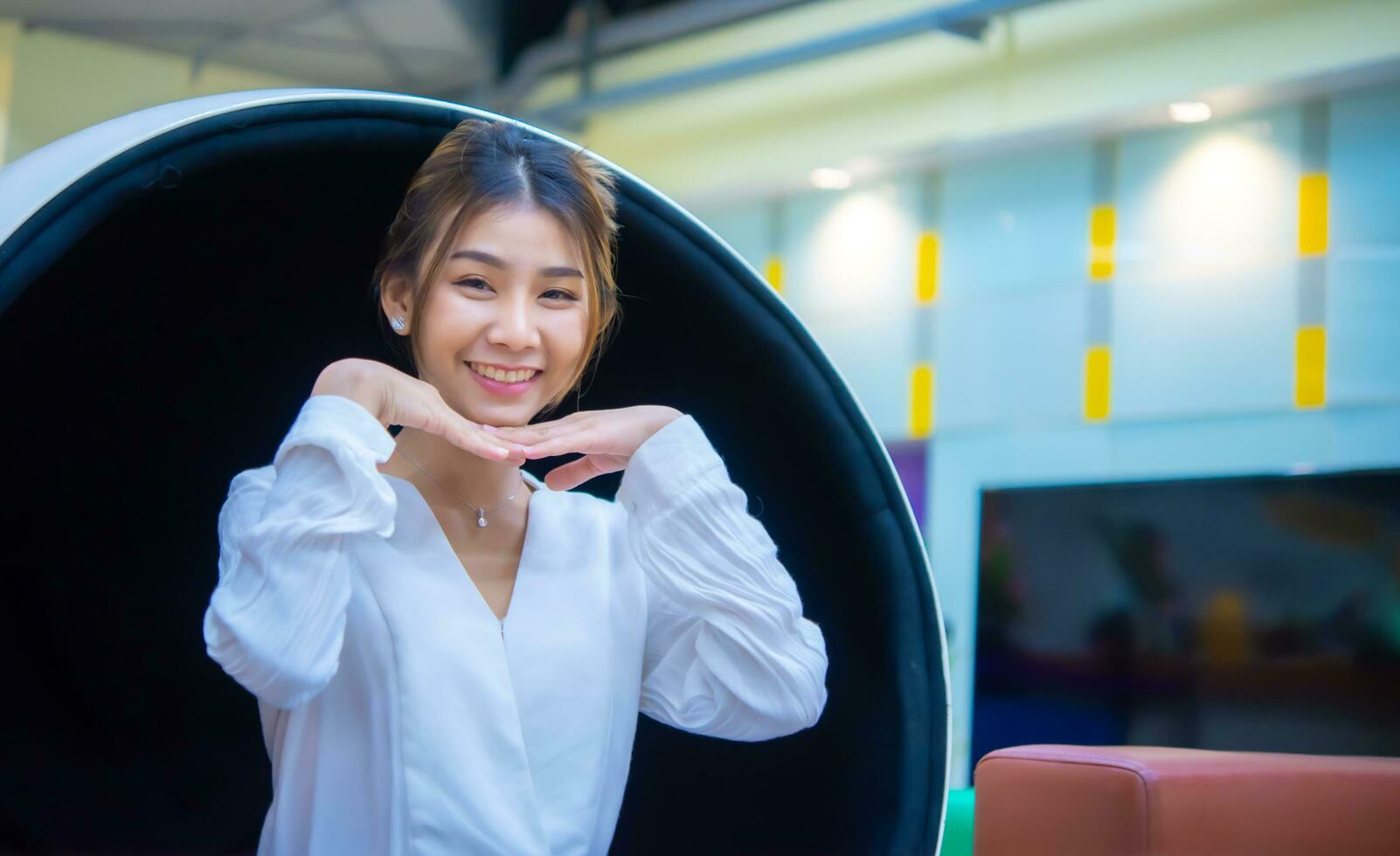 Beautiful asian business woman sitting on the modern round chair and smiling to the camera is a powerful representation of the qualities that make her an effective and success, Digital marketing. photo