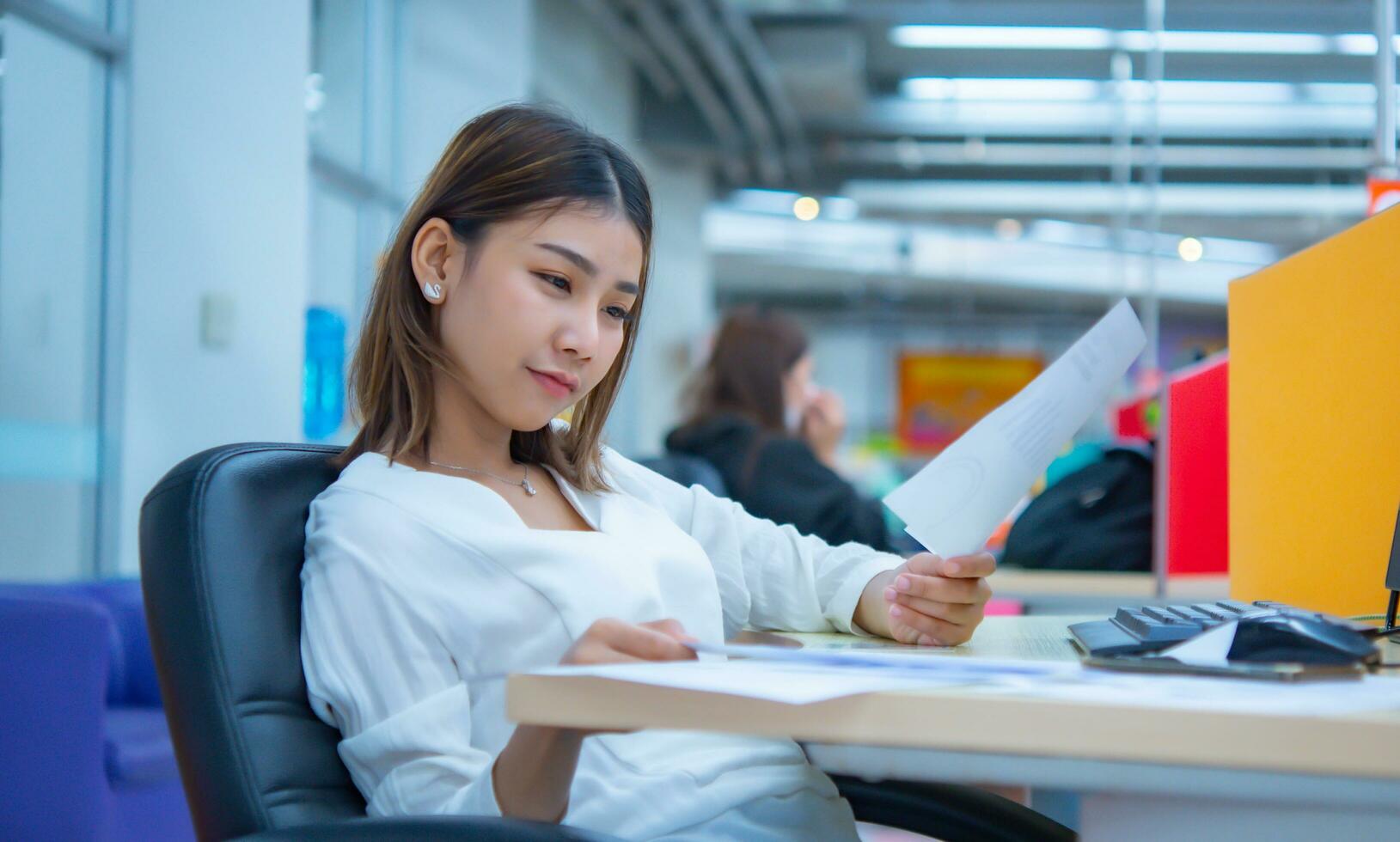 Beautiful asian business woman is looking at the company's financial documents with a smile, Digital marketing. photo